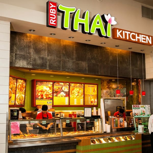 Ruby Thai Kitchen restaurant counter with illuminated menu boards, food display, staff, and customers in a shopping mall.